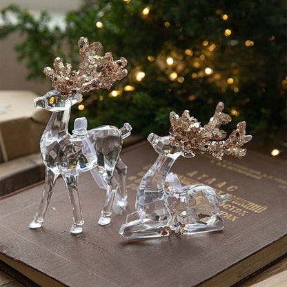 Crystal reindeer figurines with decorative antlers on a book with a blurred Christmas tree in the background.