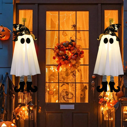 Halloween decorations on a door with ghosts, pumpkins, and a wreath.